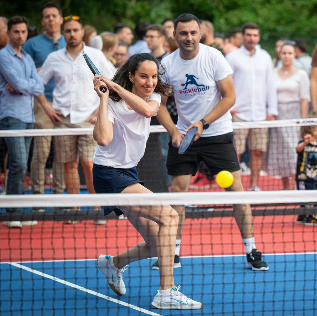 a woman hitting a ball with a pickleball racket